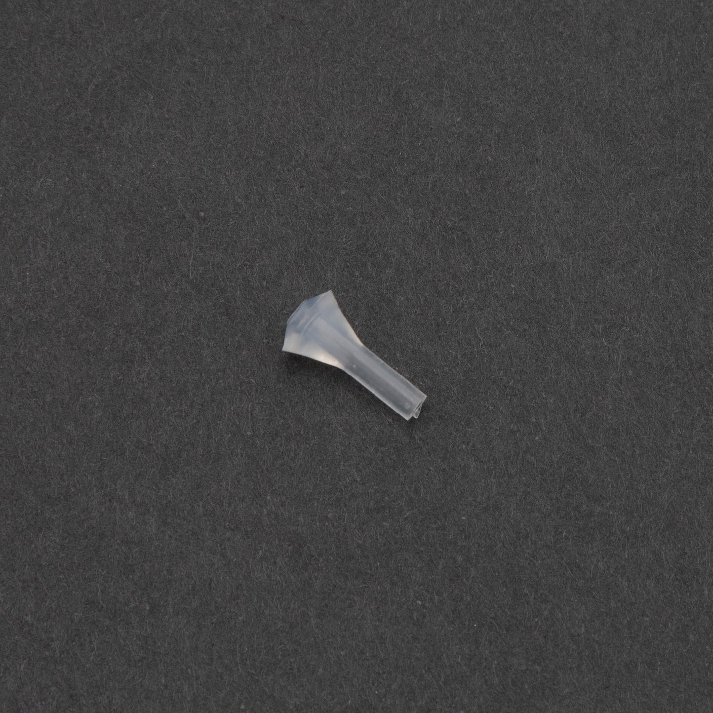A small clear plastic object rests on a smooth black surface, creating a striking contrast in color and texture.
