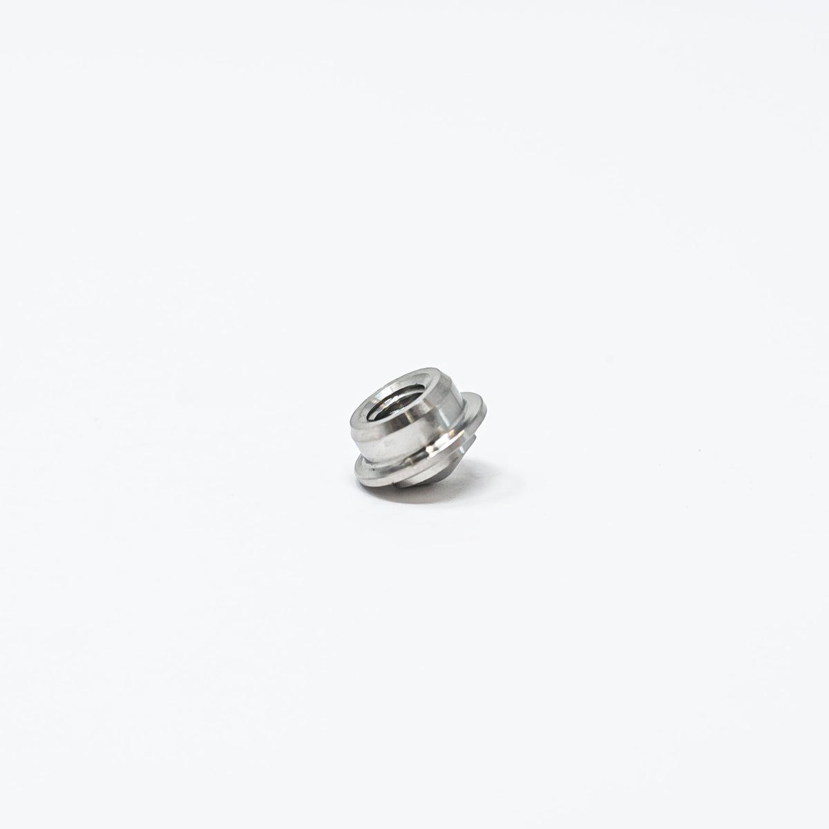 A small metal nut resting on a clean white surface, showcasing its shiny texture and circular shape.