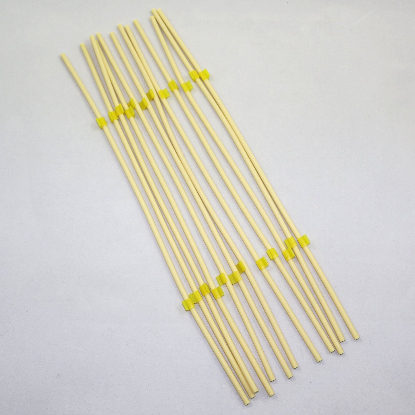 Set of yellow tubing pieces with green clips on a gray background