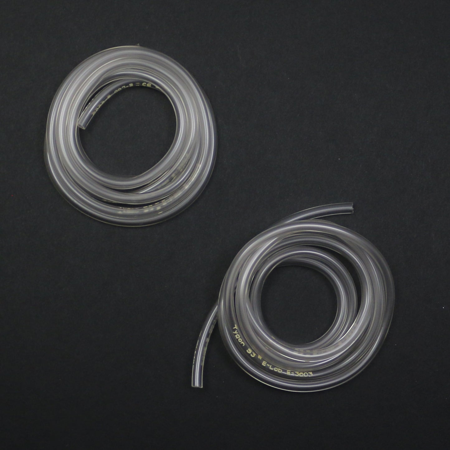 Two coiled clear silicone hoses on a black background