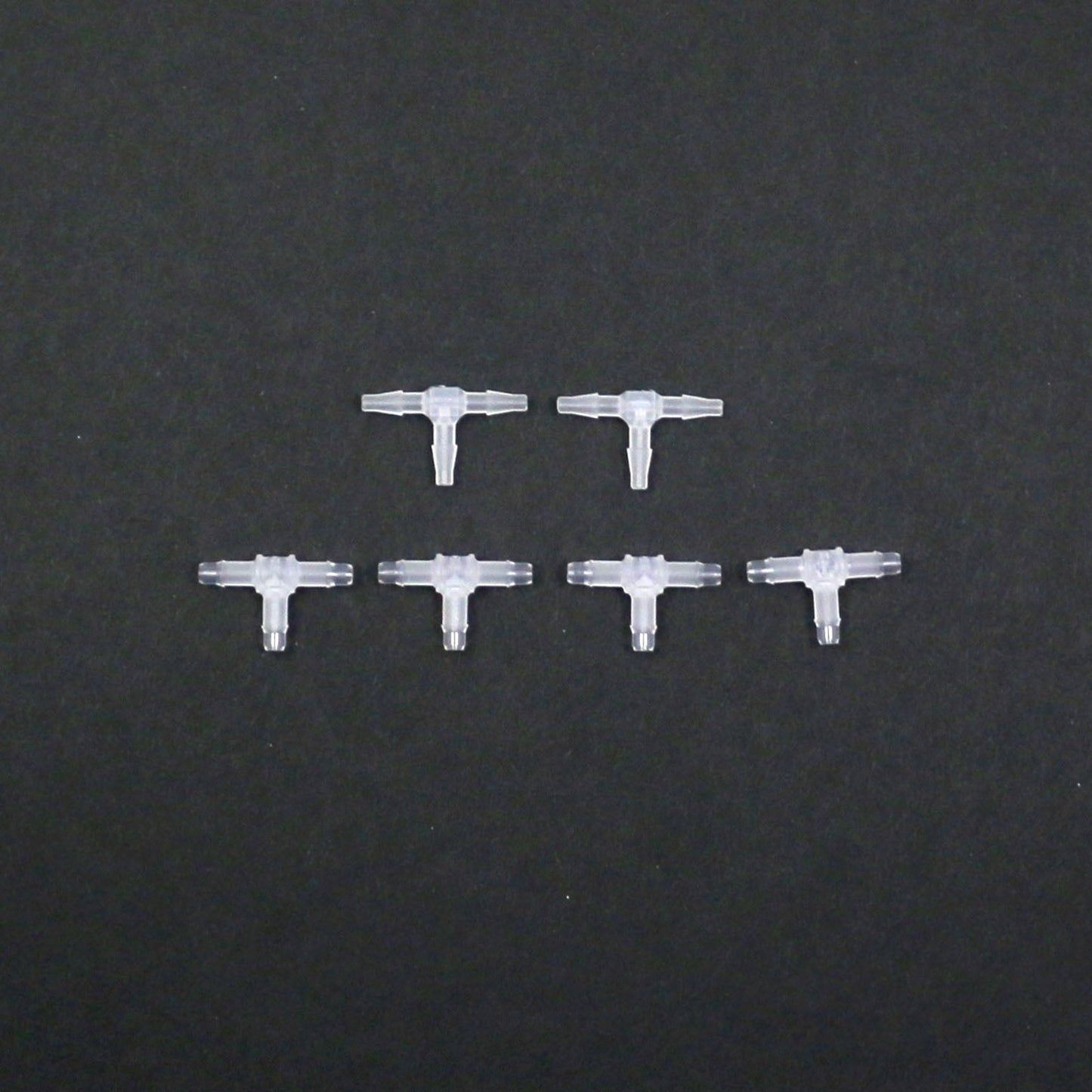 Set of six clear plastic connectors on a black background