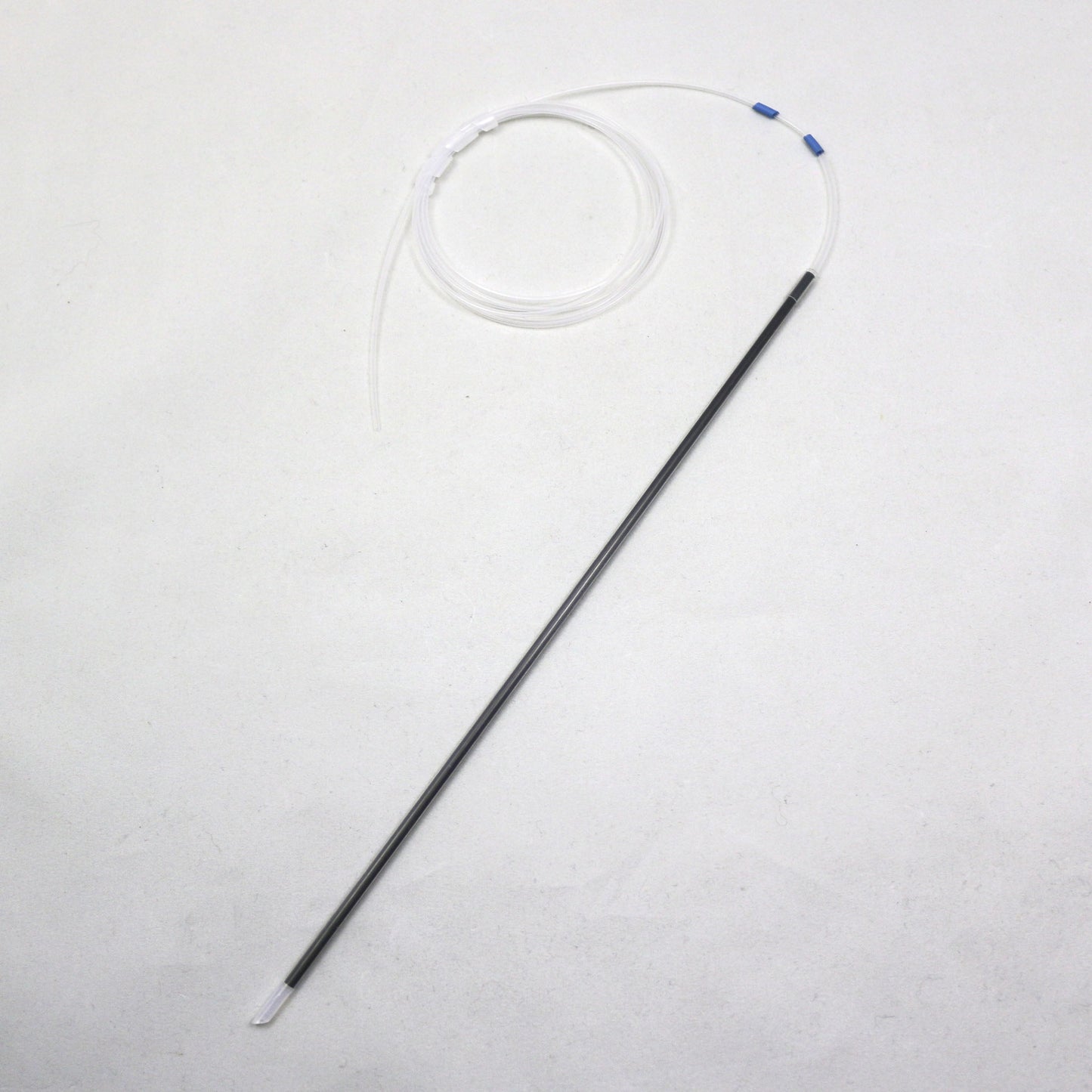 Long thin black object with a white circular component on a light gray background