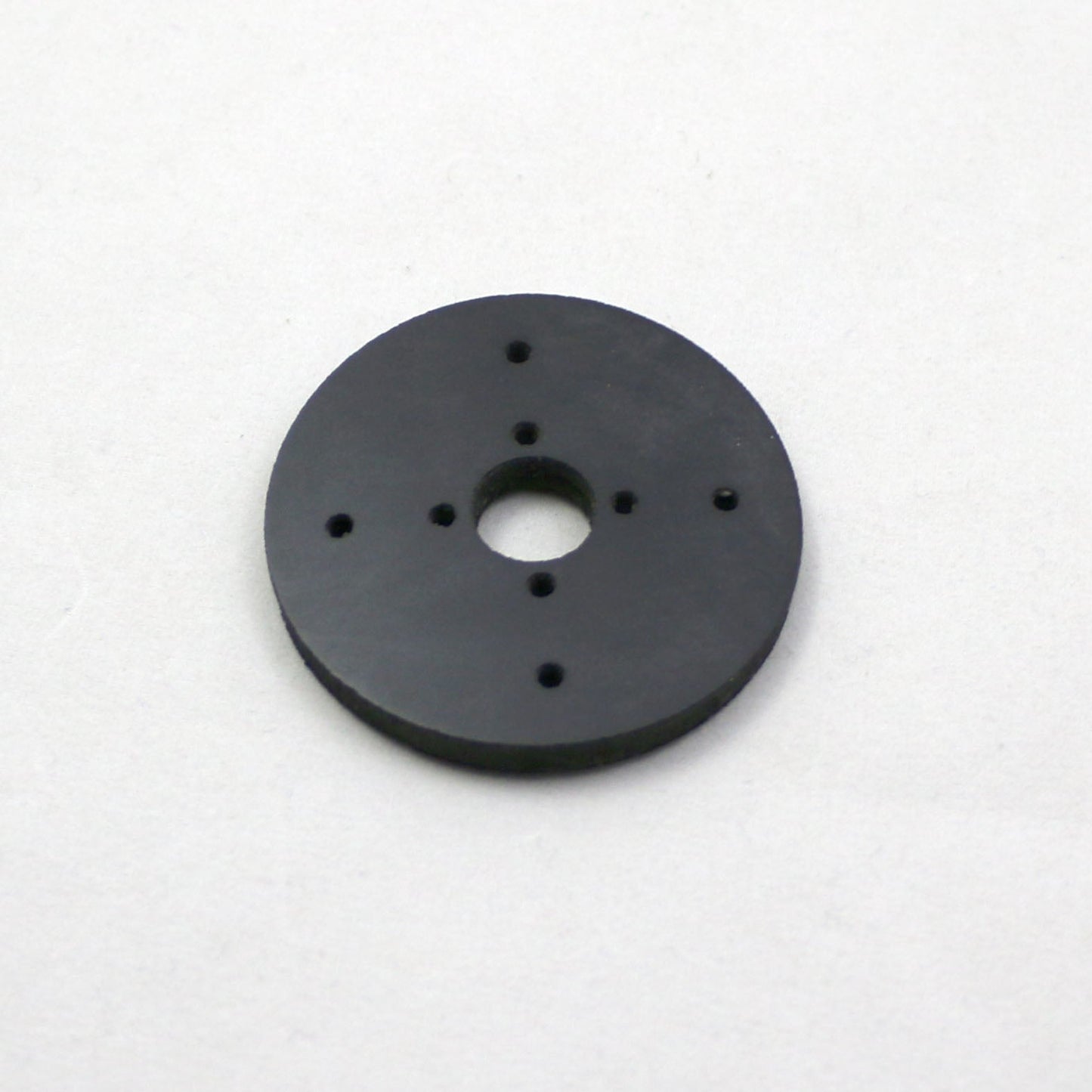 Black circular object with multiple holes on a white background