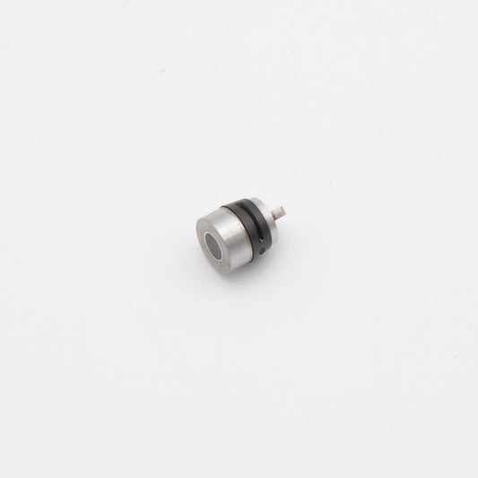 A small metal object resting on a clean white surface, showcasing its reflective surface and intricate details.