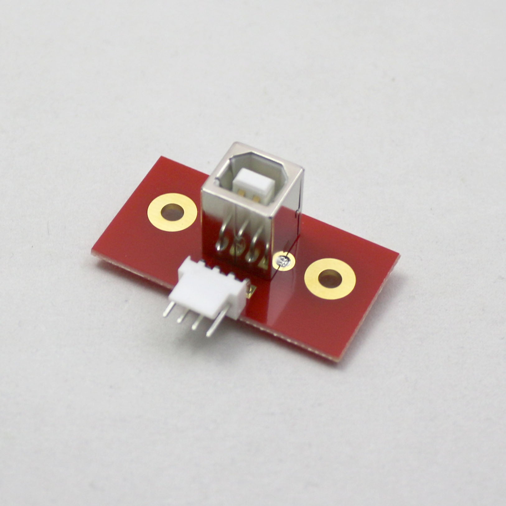 Electronic component with red board and gold contacts on a gray background