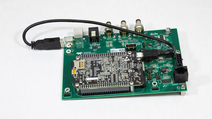A miniature electronic board featuring an attached USB cable for power or data transfer.