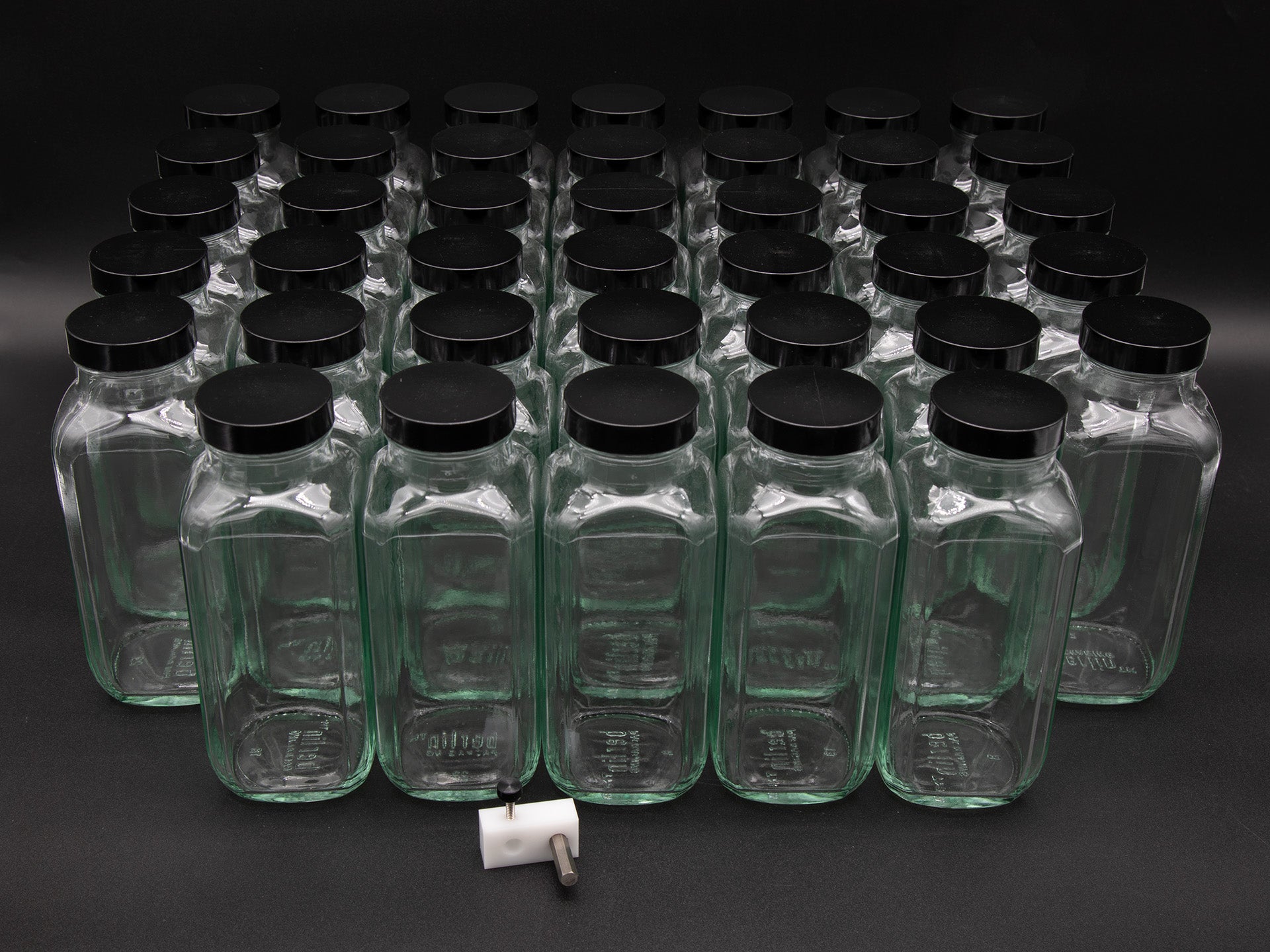 A large collection of empty glass bottles arranged against a solid black background, creating a striking visual contrast.