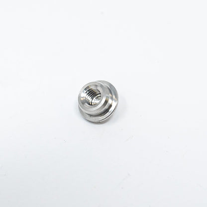 A small metal nut resting on a clean white surface, showcasing its shiny texture and circular shape.