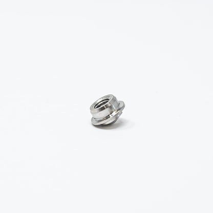 A small metal nut resting on a clean white surface, showcasing its shiny texture and circular shape.