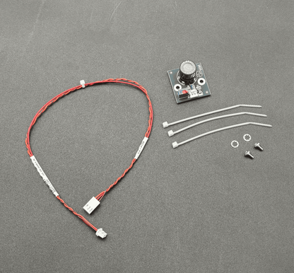 A small electronic control module kit on a dark gray textured background, including a red and white wire harness with a connector, a small circuit board with a rotary knob, three white zip ties, two screws, and two washers.