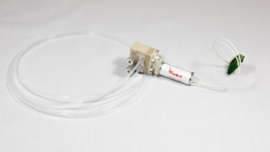A small valve with clear tubing connected, along with an electronic wire, both resting on a neutral background.