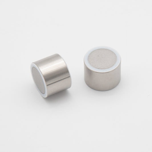 A pair of small metal cylinders adorned with white circles, displayed together, highlighting their simple yet distinct design.