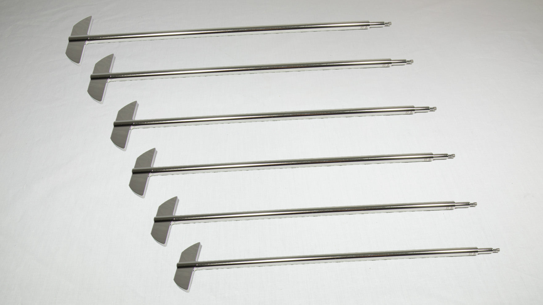 Six uniquely shaped metal rods positioned together for comparison.