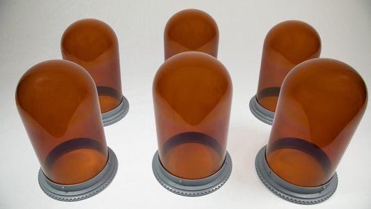 Six vibrant amber colored glass vessels with sturdy bases, showcasing a modern design on a simple surface.