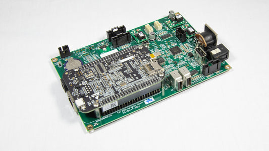 A green electronic circuit board with various components displayed on top.