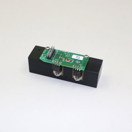 Electronic module with a green circuit board on a black base against a white background