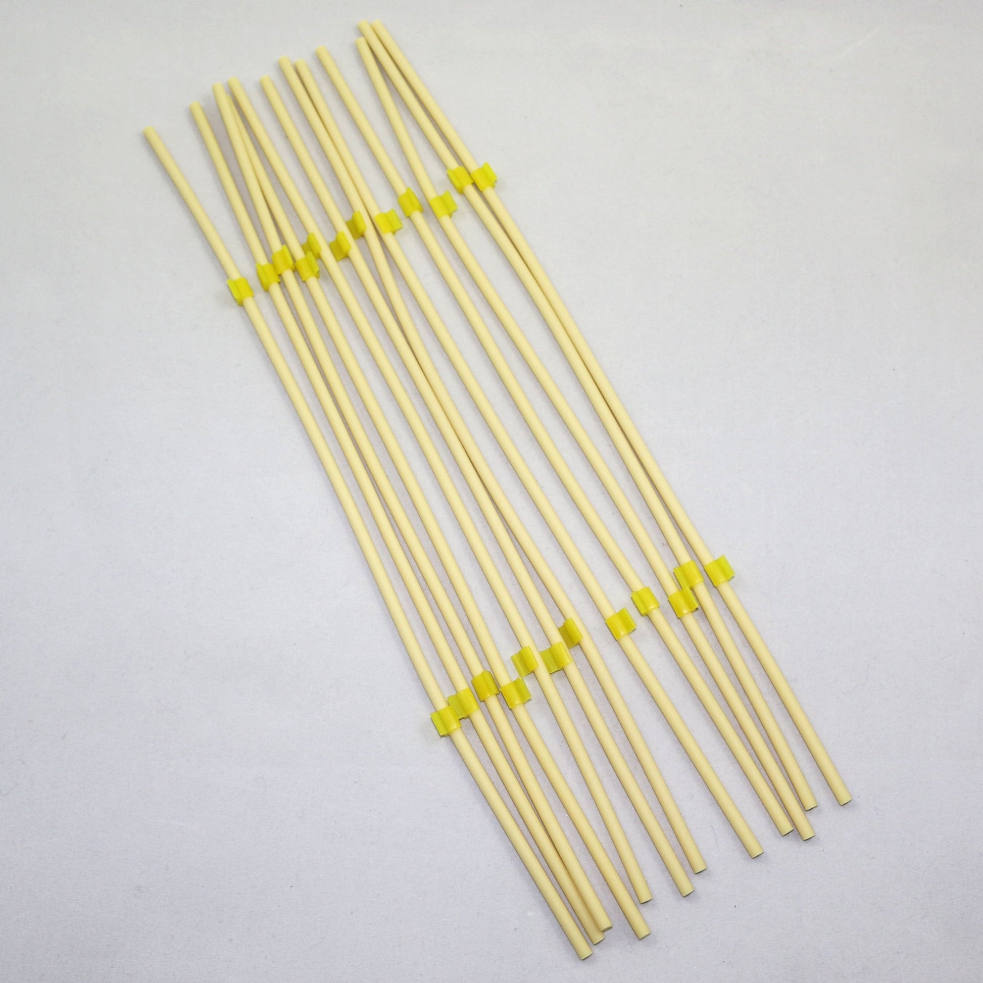 Set of yellow tubing pieces with green clips on a gray background