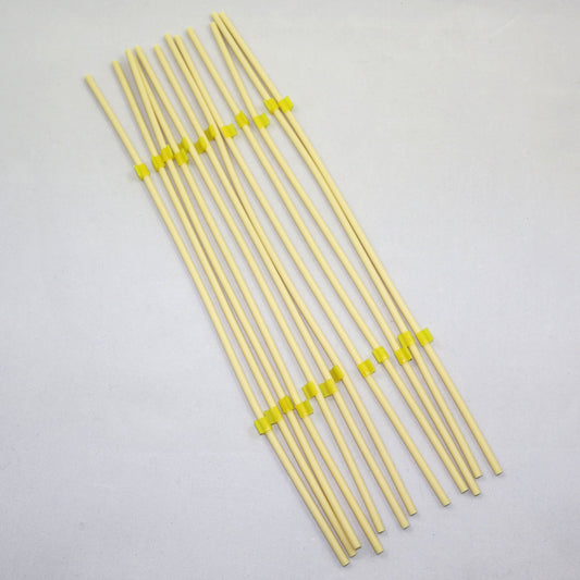 Set of yellow tubing pieces with green clips on a gray background