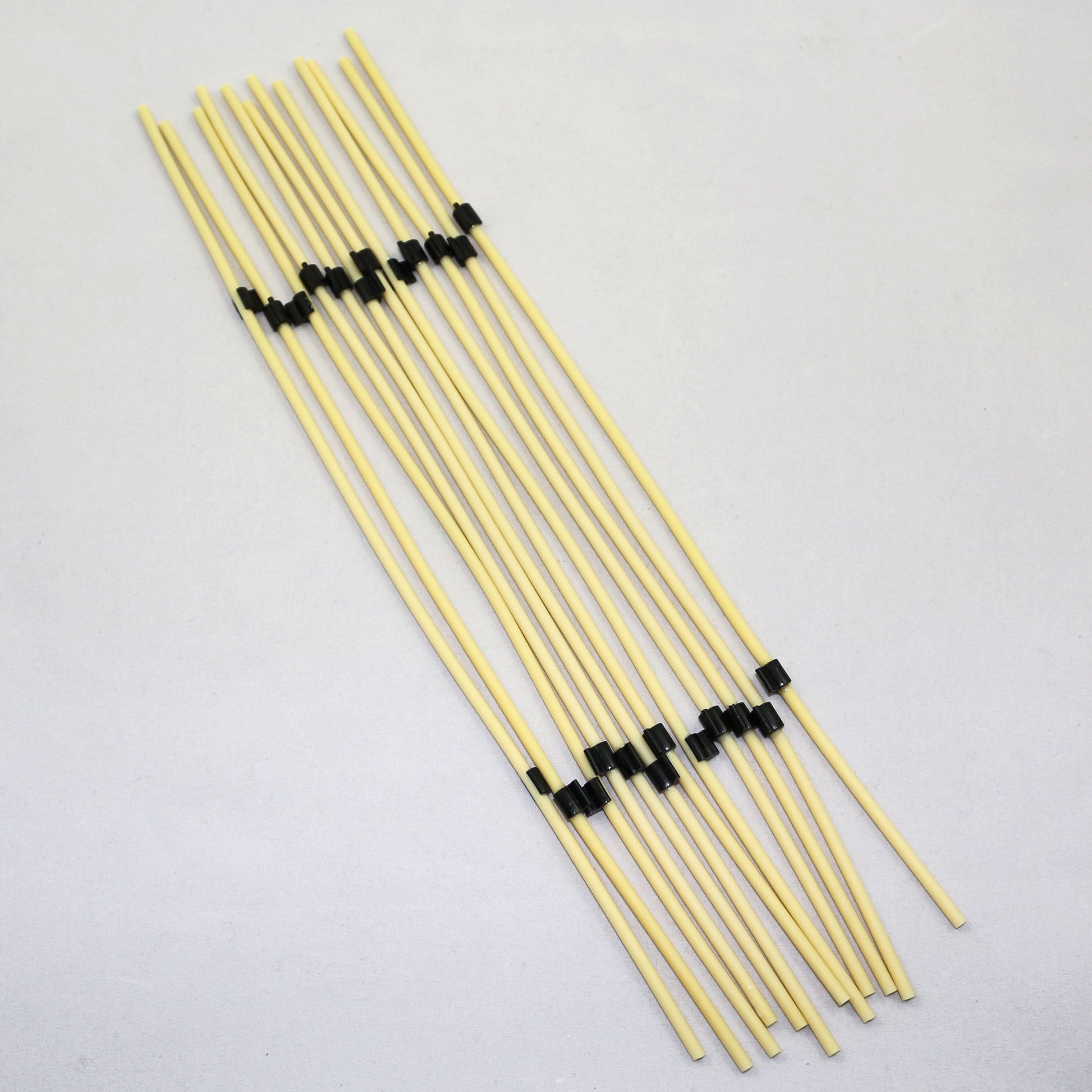 Set of yellow tubing pieces with black ends on a light gray background