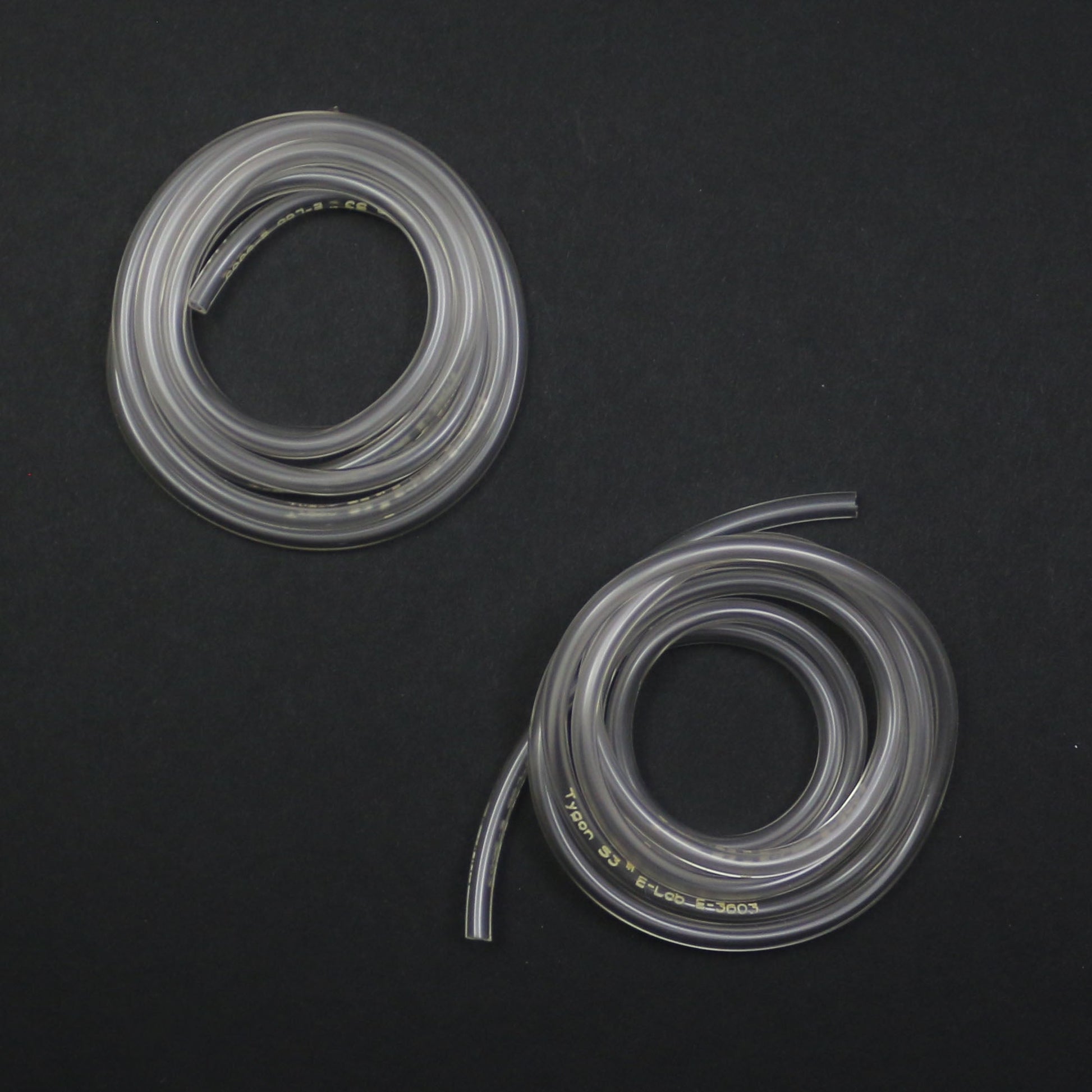 Two coiled clear silicone hoses on a black background