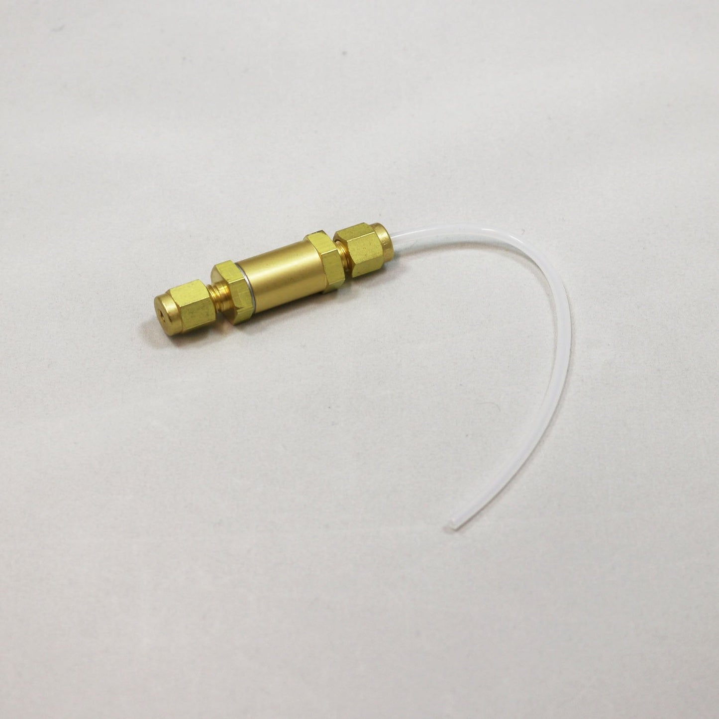 Brass connector with a piece of white tubing on a light gray background