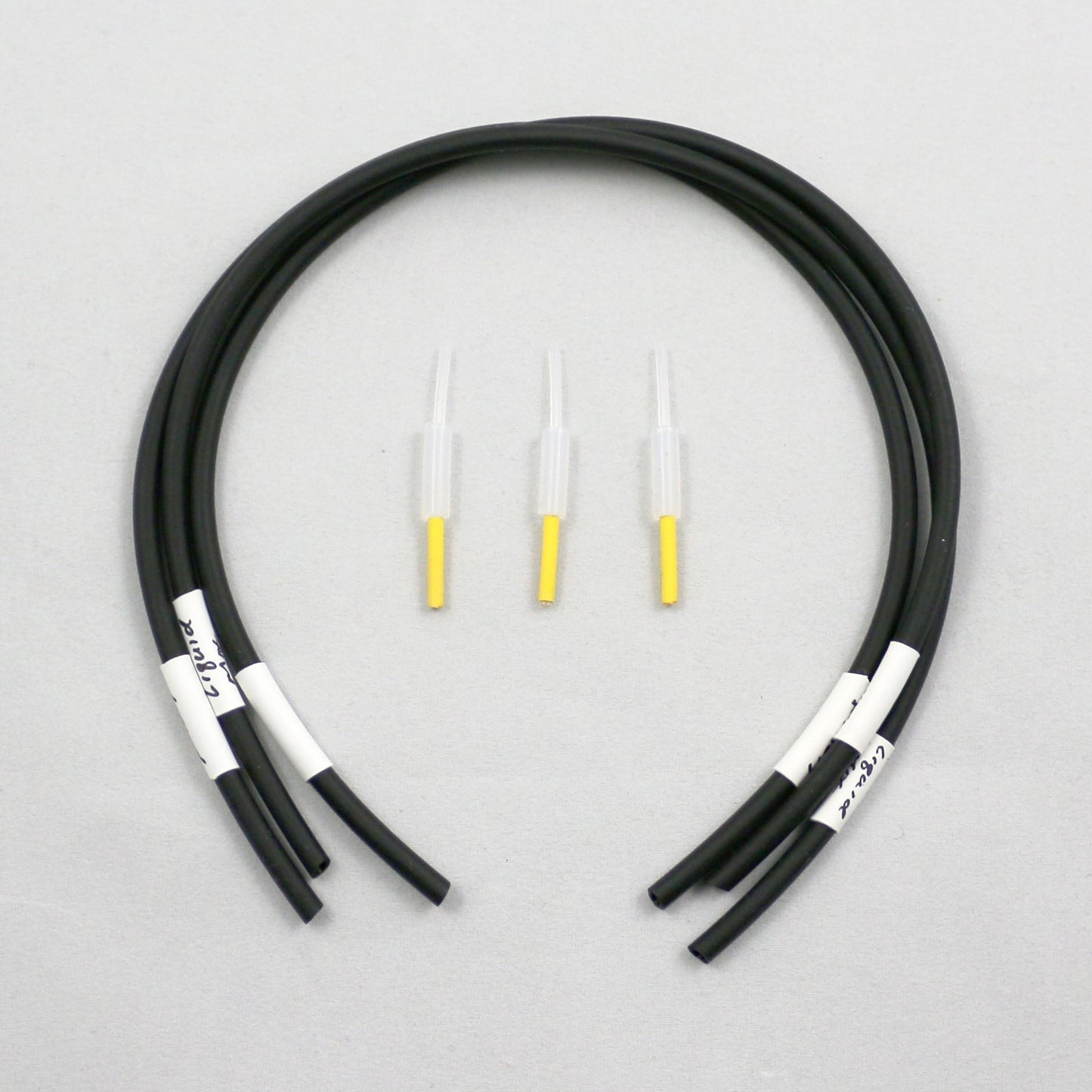 Black tubing pieces with plastic connectors on a gray background