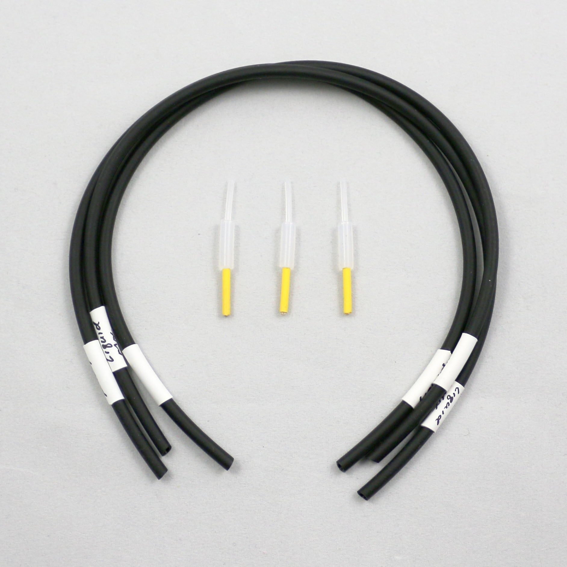 Black tubing pieces with plastic connectors on a gray background
