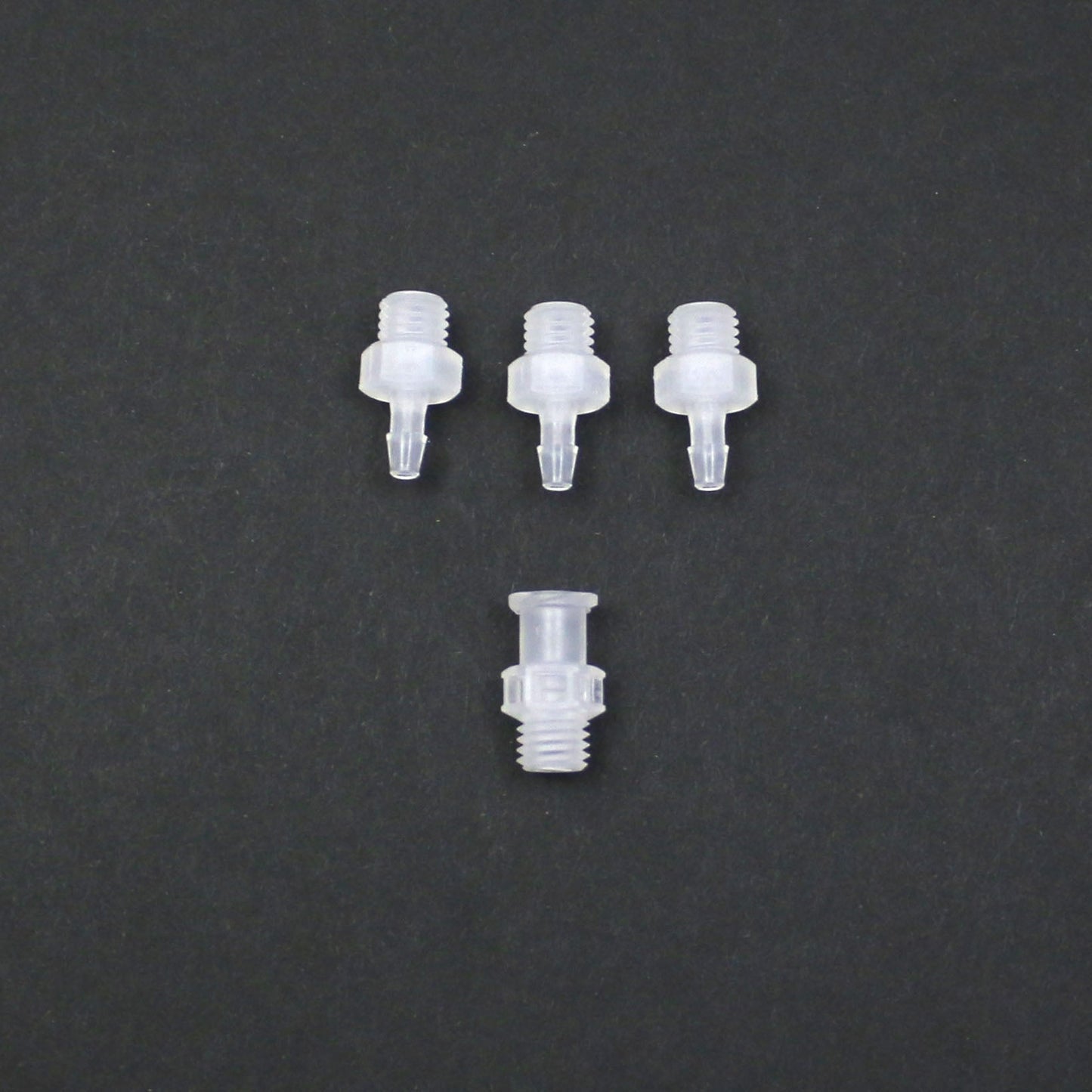 Four clear plastic nozzles on a dark gray background