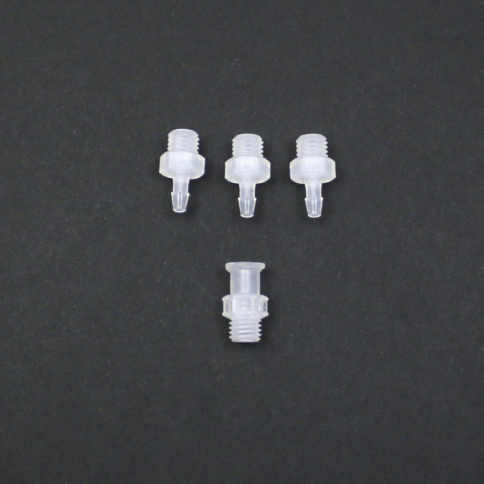 Four clear plastic nozzles on a dark gray background