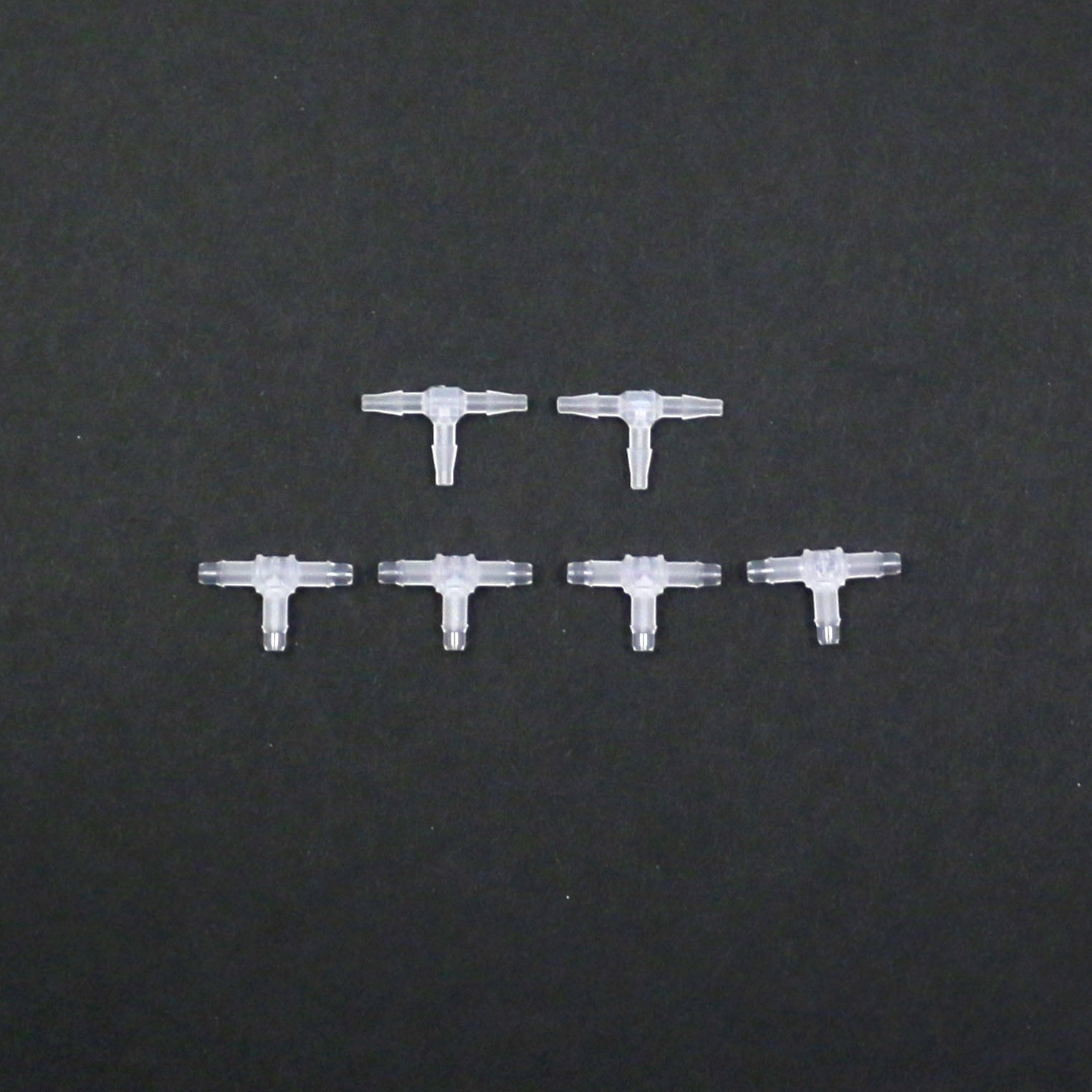 Set of six clear plastic connectors on a black background