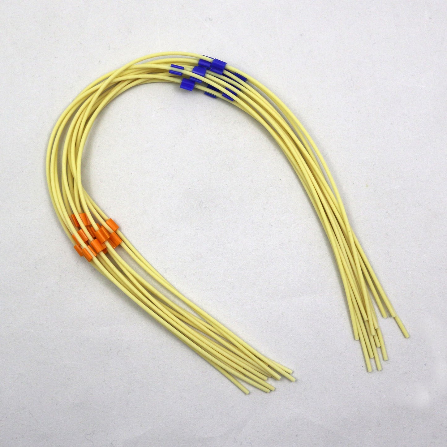 Pieces of yellow tubing with color-coded markers on a white background