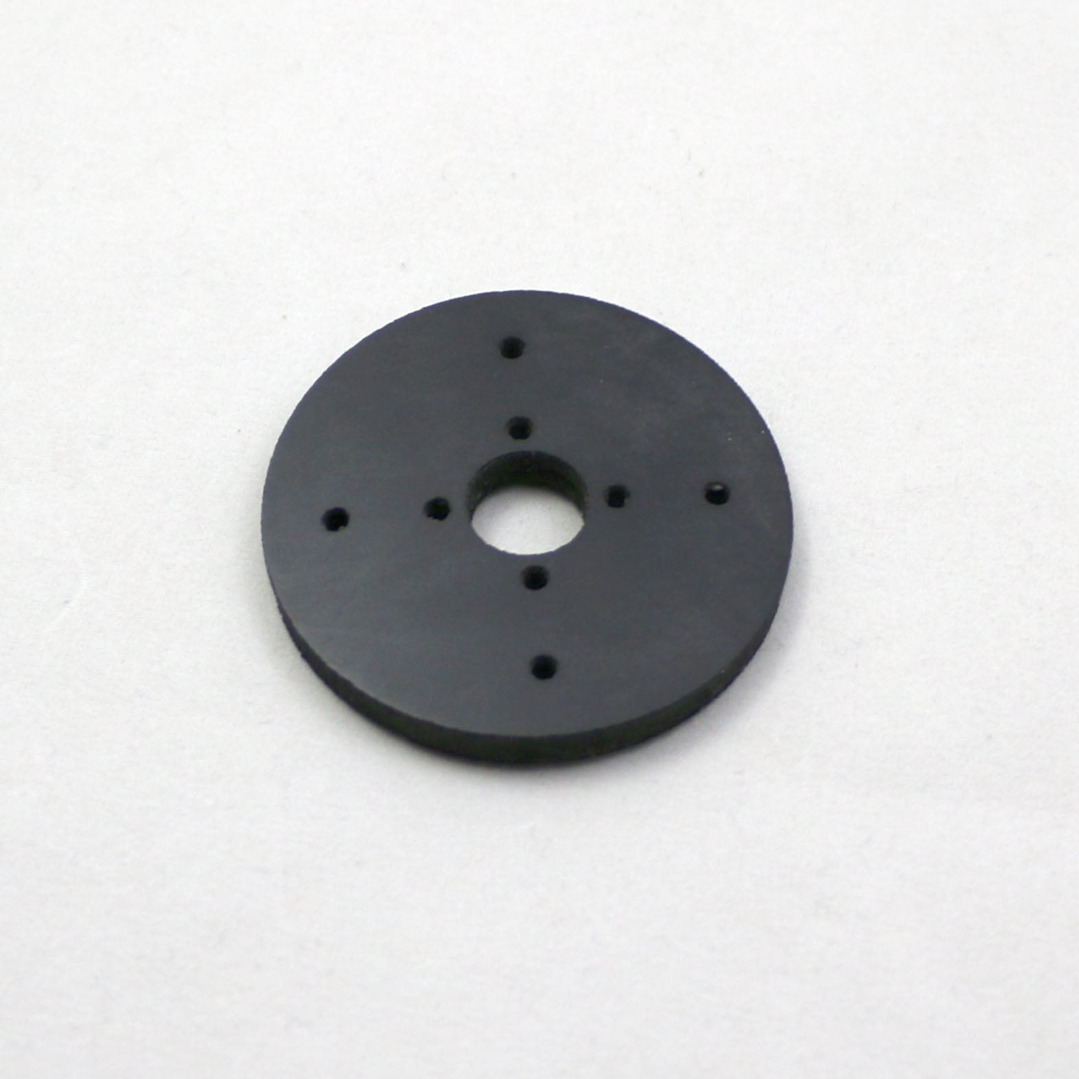 Black circular object with multiple holes on a white background