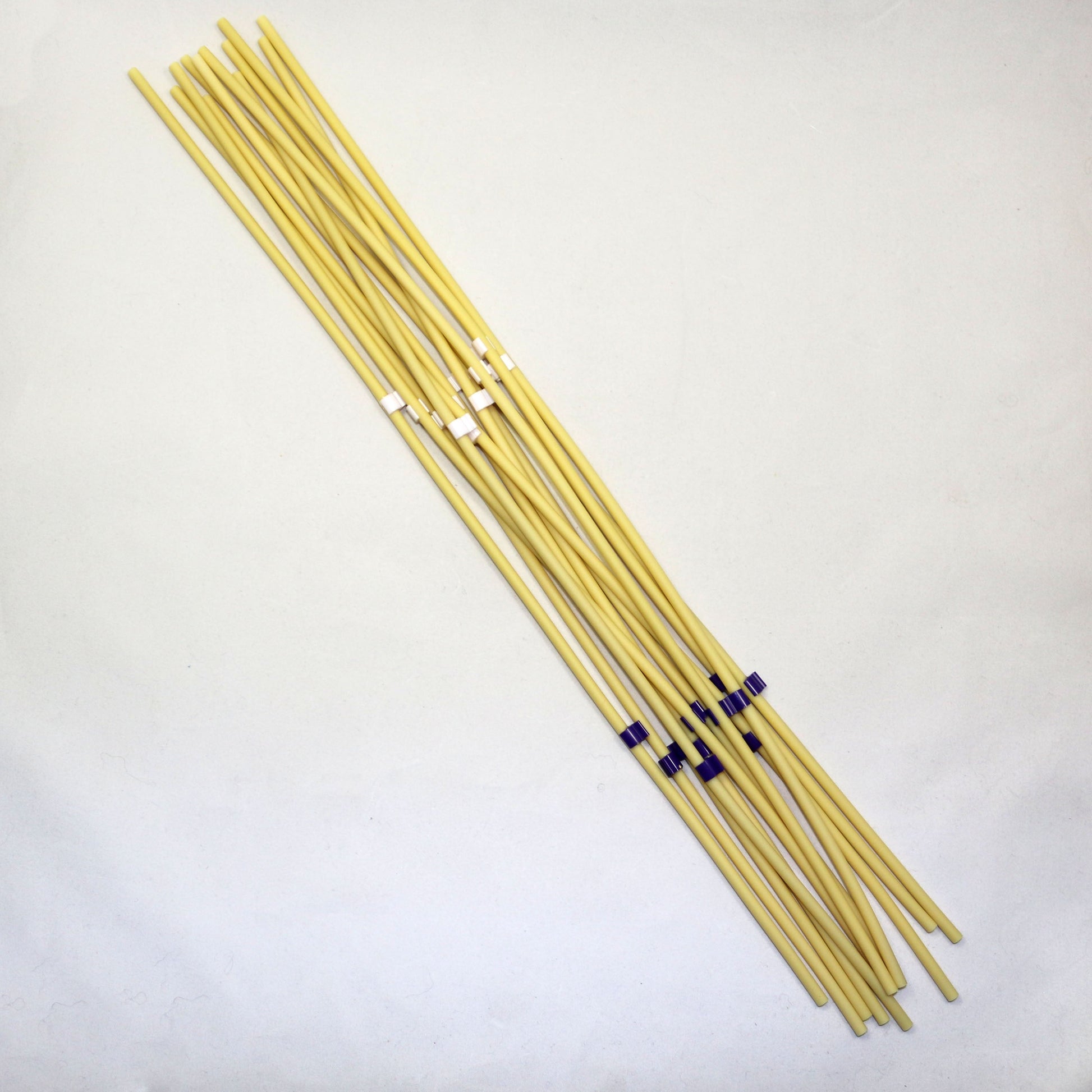 Set of yellow tubing pieces with black ends on a light gray background