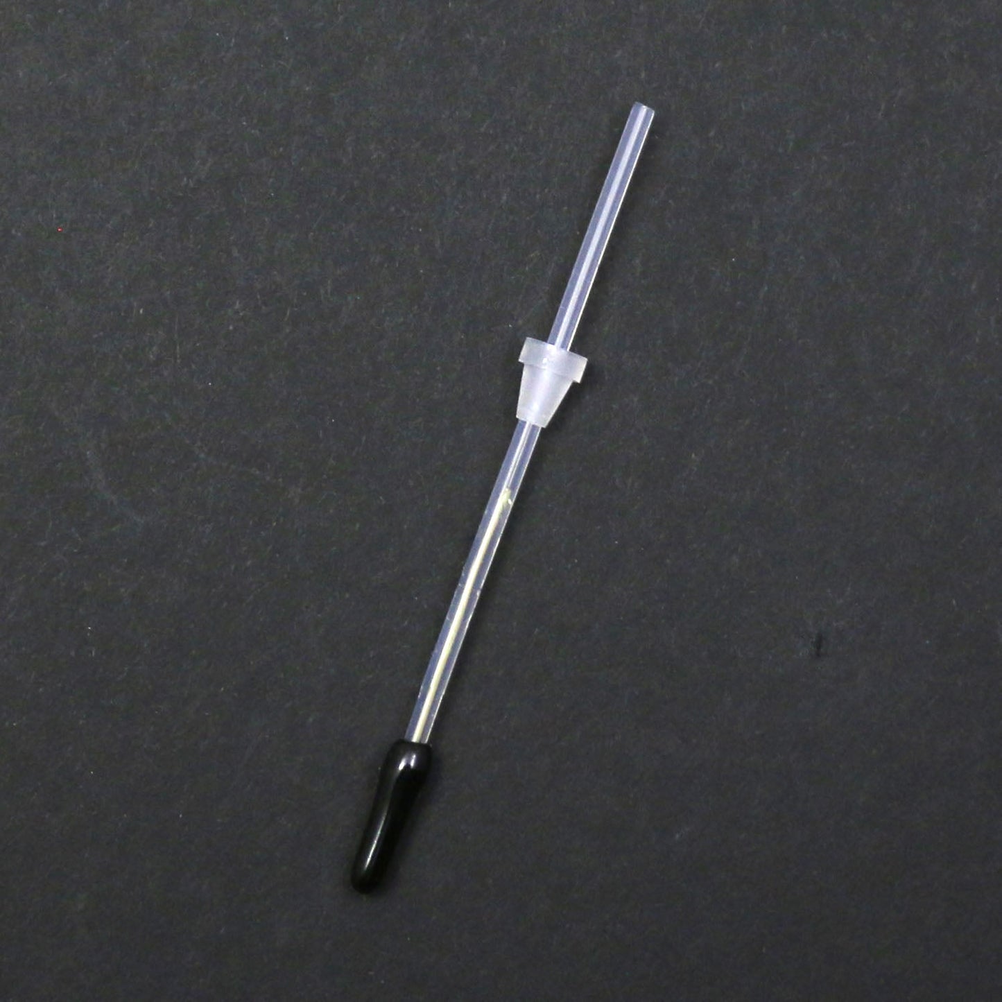 Thin metal rod with a black tip on a gray background
