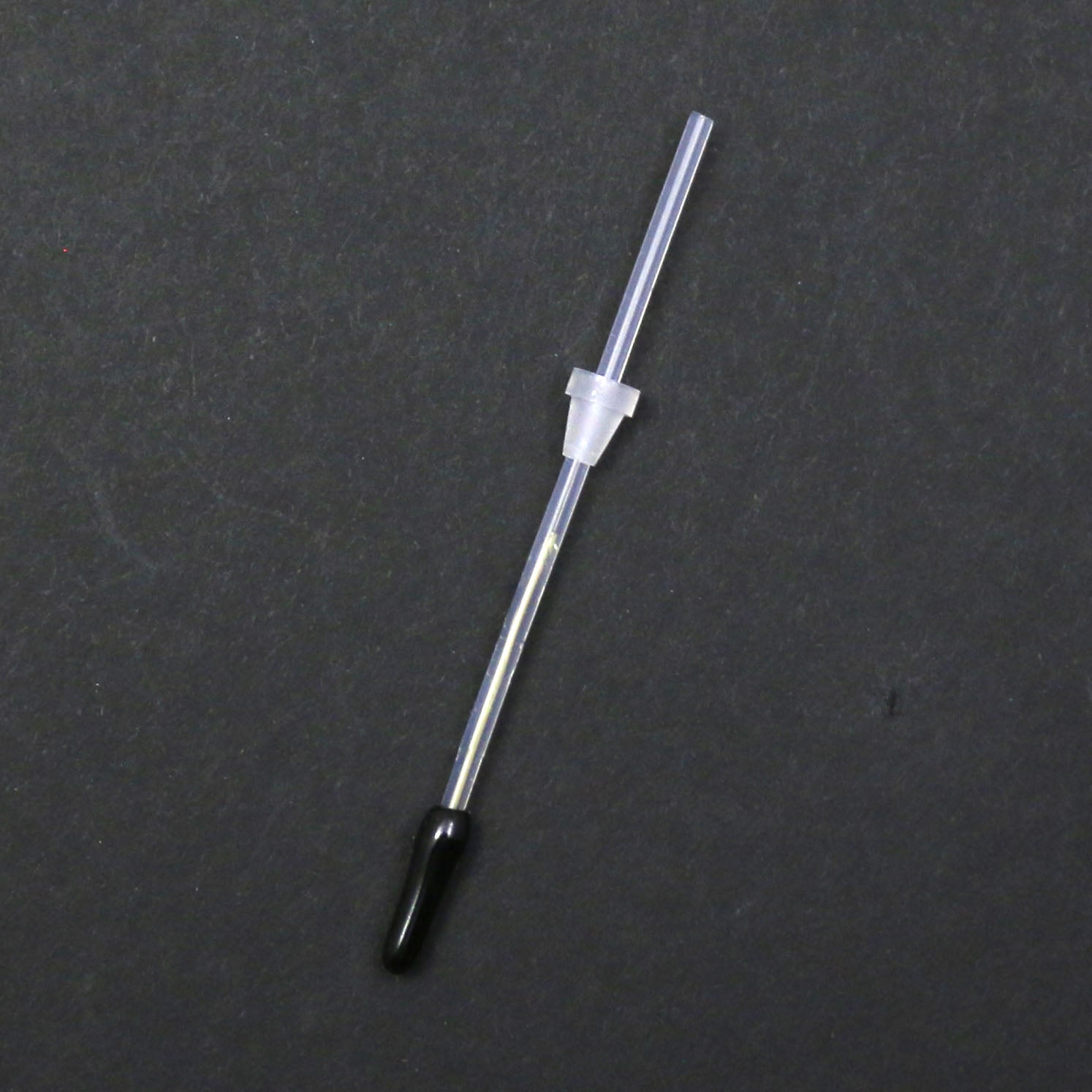 Thin metal rod with a black tip on a gray background