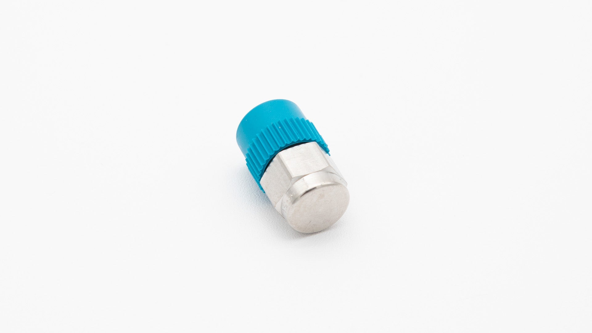 A blue plastic threaded fitting placed on a clean white surface, showcasing its design and color contrast.