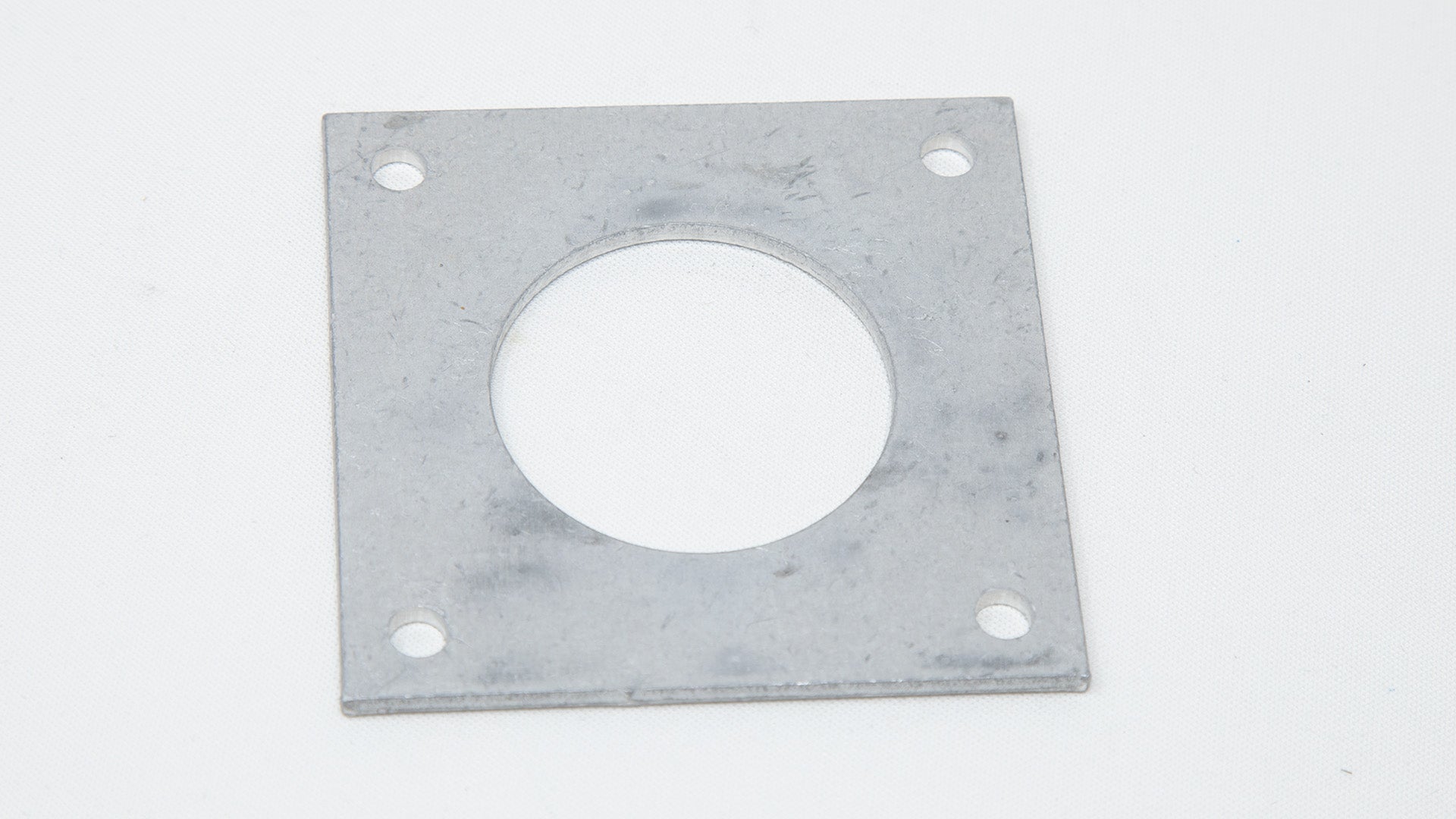 Square plate with a small hole in each corner and a large hole in middle.