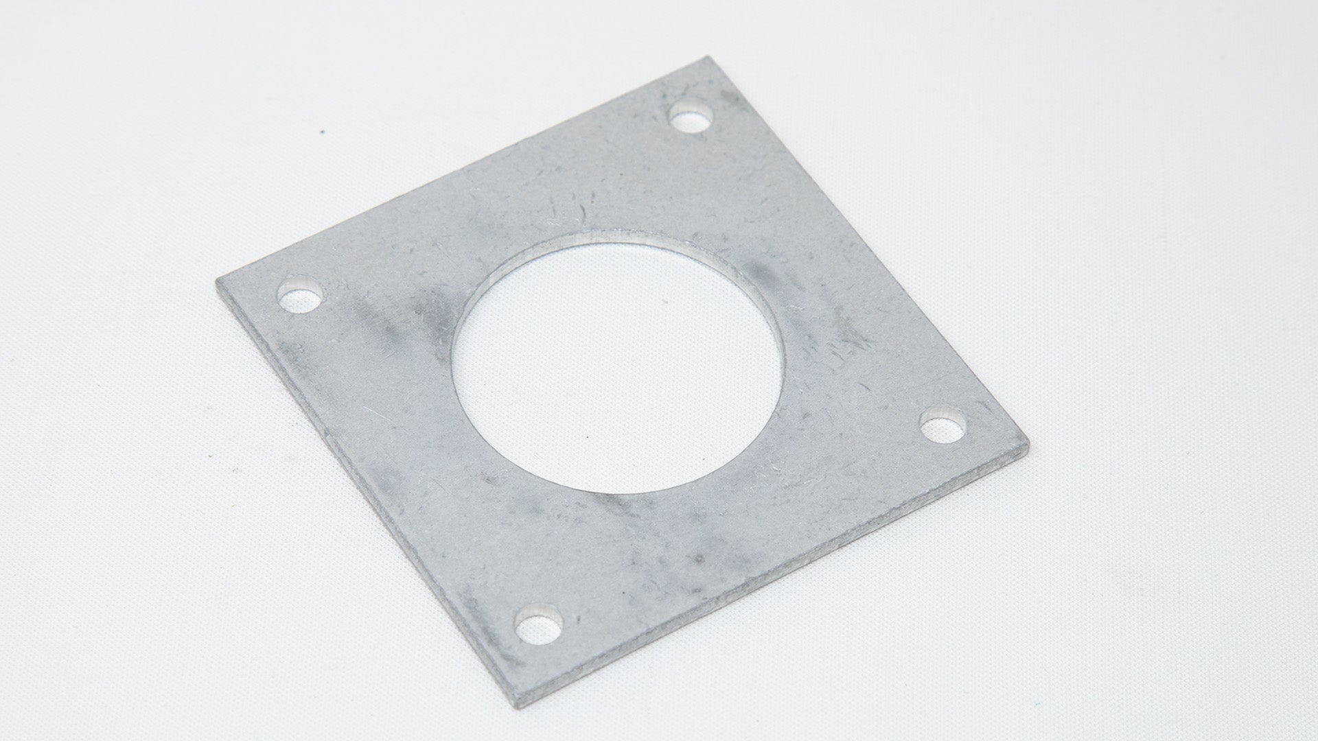 Square plate with a small hole in each corner and a large hole in middle.